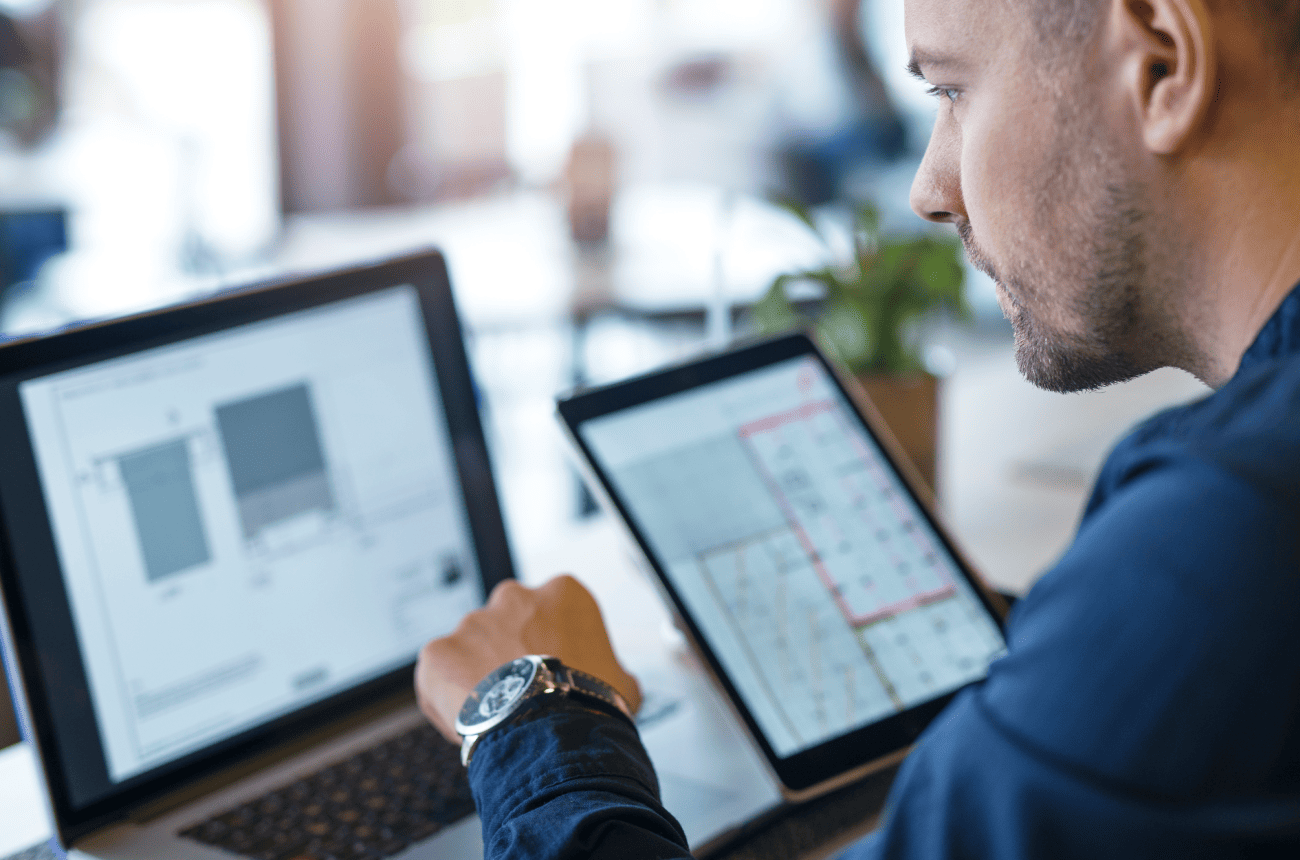 Business professional reviewing operational information on a laptop and tablet